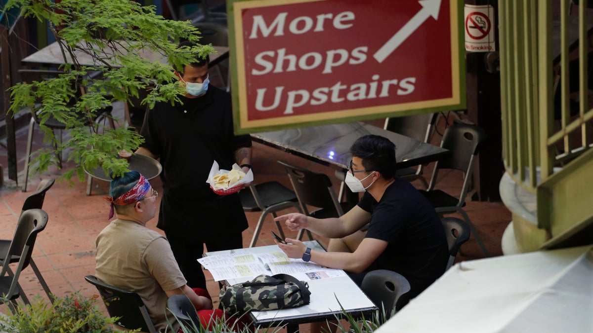 A waiter serves a group dining at a restaurant that reopened at the River Walk in San Antonio, Friday, May 1, 2020. (Associated Press)