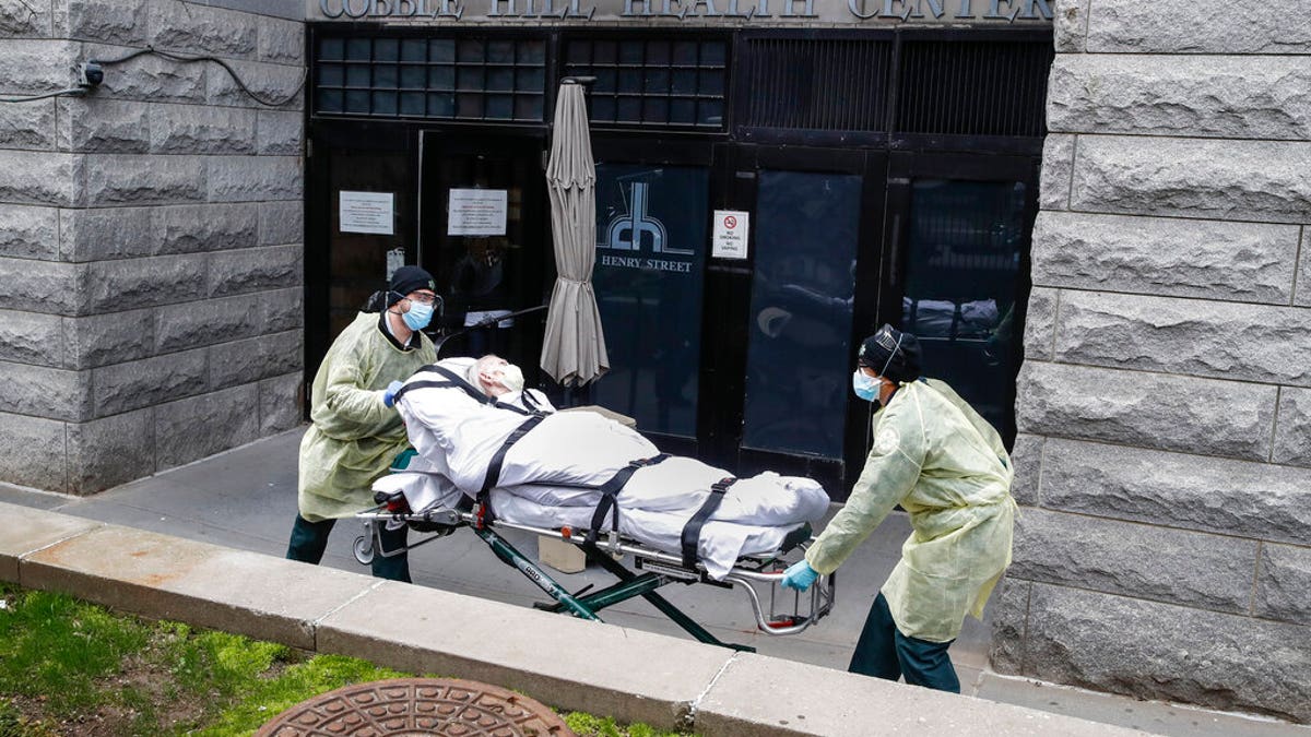 FILE - In this Friday, April 17, 2020 file photo, a patient is wheeled out of the Cobble Hill Health Center by emergency medical workers in the Brooklyn borough of New York.  (AP Photo/John Minchillo)