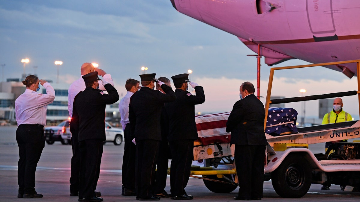 Ambulnz paramedics and Aurora firefighters salute as the casket carrying the body of paramedic Paul Cary is removed from a plane at Denver International Airport on Sunday, May 3, 2020, in Denver. Cary died from coronavirus after volunteering to help combat the pandemic in New York City. (Helen H. Richardson/The Denver Post via AP, Pool)