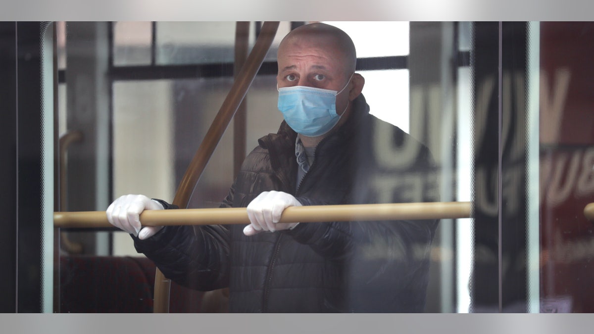 A man wears a mask to protect against the coronavirus as he looks out of the window of a bus in London, Monday, May 4, 2020, as the UK enters a seventh week of lockdown to help stop the spread of coronavirus. The highly contagious COVID-19 coronavirus has impacted on nations around the globe, many imposing self isolation and exercising social distancing when people move from their homes.