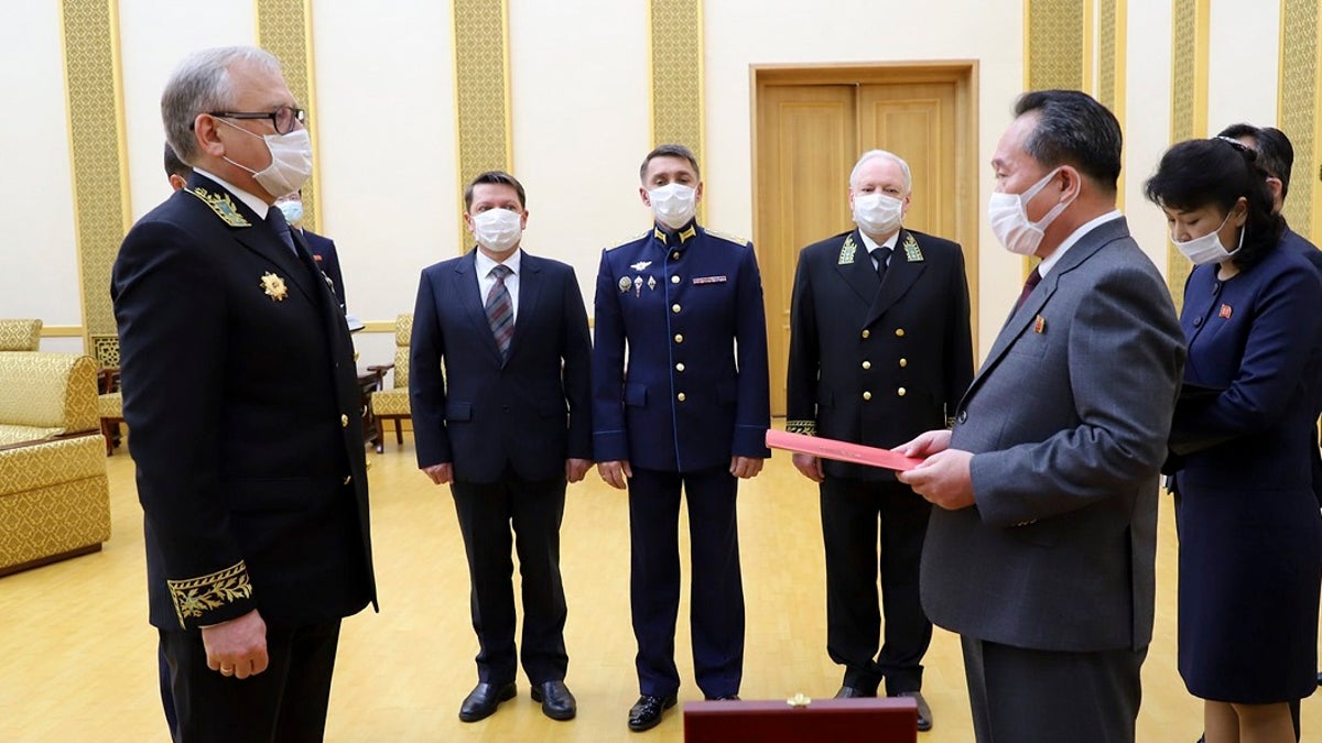 Russian Ambassador to Democratic People's Republic of Korea Alexander Matsegora, left, and Democratic People's Republic of Korea Foreign Minister Ri Son-gwon, foreground right, both wearing face masks to protect against coronavirus, attend a ceremony of awarding North Korean leader Kim Jong-un with Russia's 75th anniversary Victory medal for his major contribution in commemorating Soviet soldiers, who died in 1945 during Korea's liberation, at the Mansudae Palace of Congress in Pyongyang, North Korea. (Russian Embassy in the DPRK/Russian Foreign Ministry Press Service via AP)