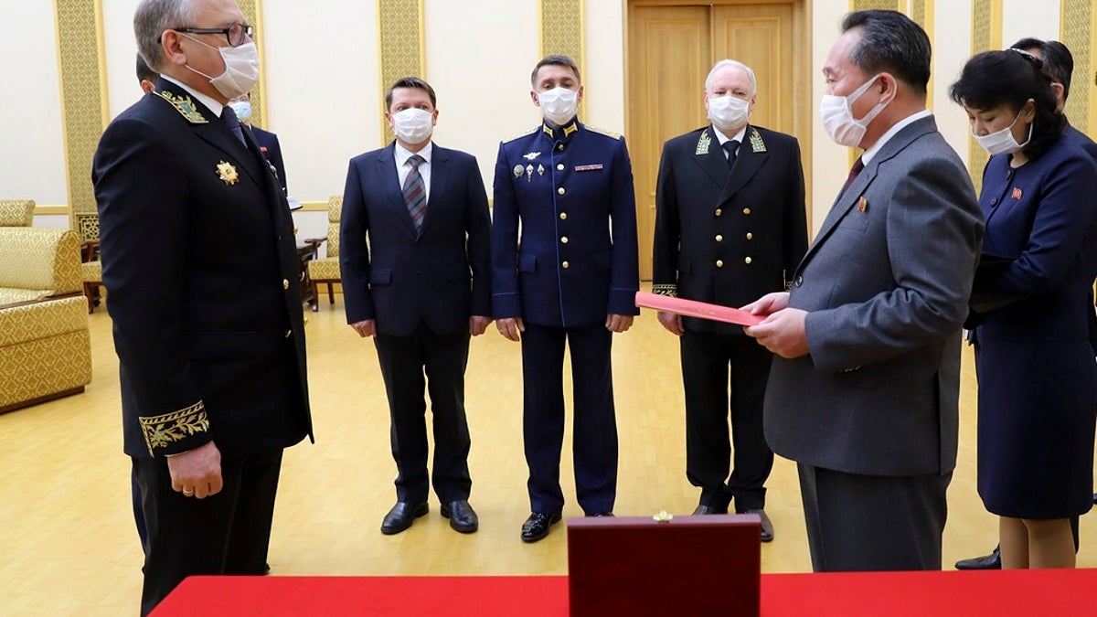 Russian Ambassador to Democratic People's Republic of Korea Alexander Matsegora, left, and Democratic People's Republic of Korea Foreign Minister Ri Son-gwon, foreground right, both wearing face masks to protect against coronavirus, attend a ceremony of awarding North Korean leader Kim Jong-un with Russia's 75th anniversary Victory medal for his major contribution in commemorating Soviet soldiers, who died in 1945 during Korea's liberation, at the Mansudae Palace of Congress in Pyongyang, North Korea. (Russian Embassy in the DPRK/Russian Foreign Ministry Press Service via AP)