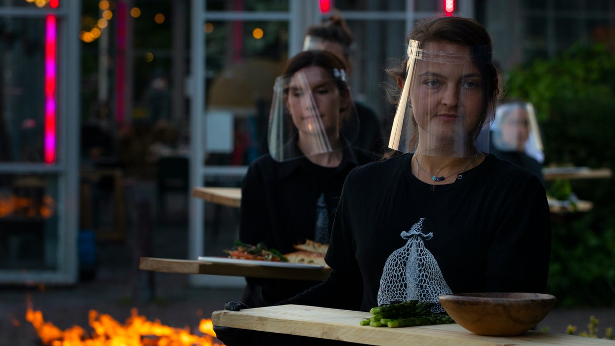 Staff at the Mediamatic restaurant serve food to volunteers seated in small glasshouses during a try-out of a setup which respects social distancing abiding by government directives to combat the spread of the COVID-19 coronavirus in Amsterdam, Netherlands, Tuesday, May 5, 2020. (AP Photo/Peter Dejong)