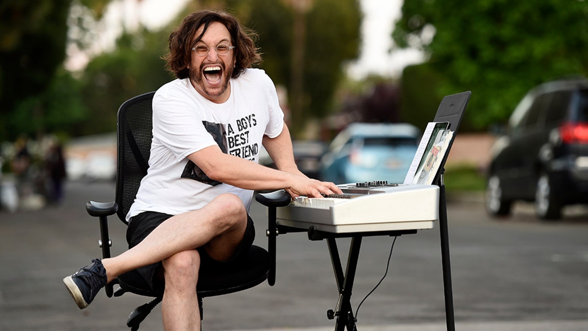 In this May 9, 2020 photo, musician Adam Chester mugs for a portrait on his street after performing his weekly neighborhood concert in the Sherman Oaks section of Los Angeles. (AP Photo/Chris Pizzello)