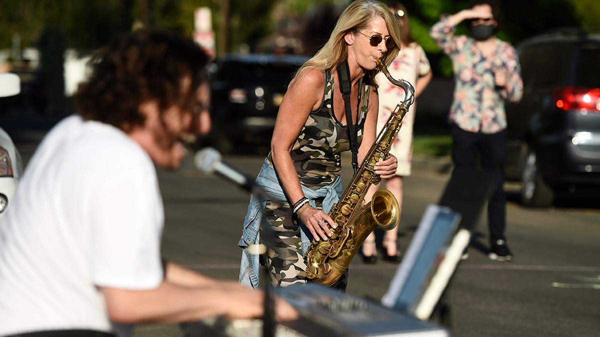 In this May 9, 2020 photo, musician Adam Chester, left, is joined by saxophonist Katja Rieckermann during his weekly neighborhood concert in the Sherman Oaks section of Los Angeles. (AP Photo/Chris Pizzello)