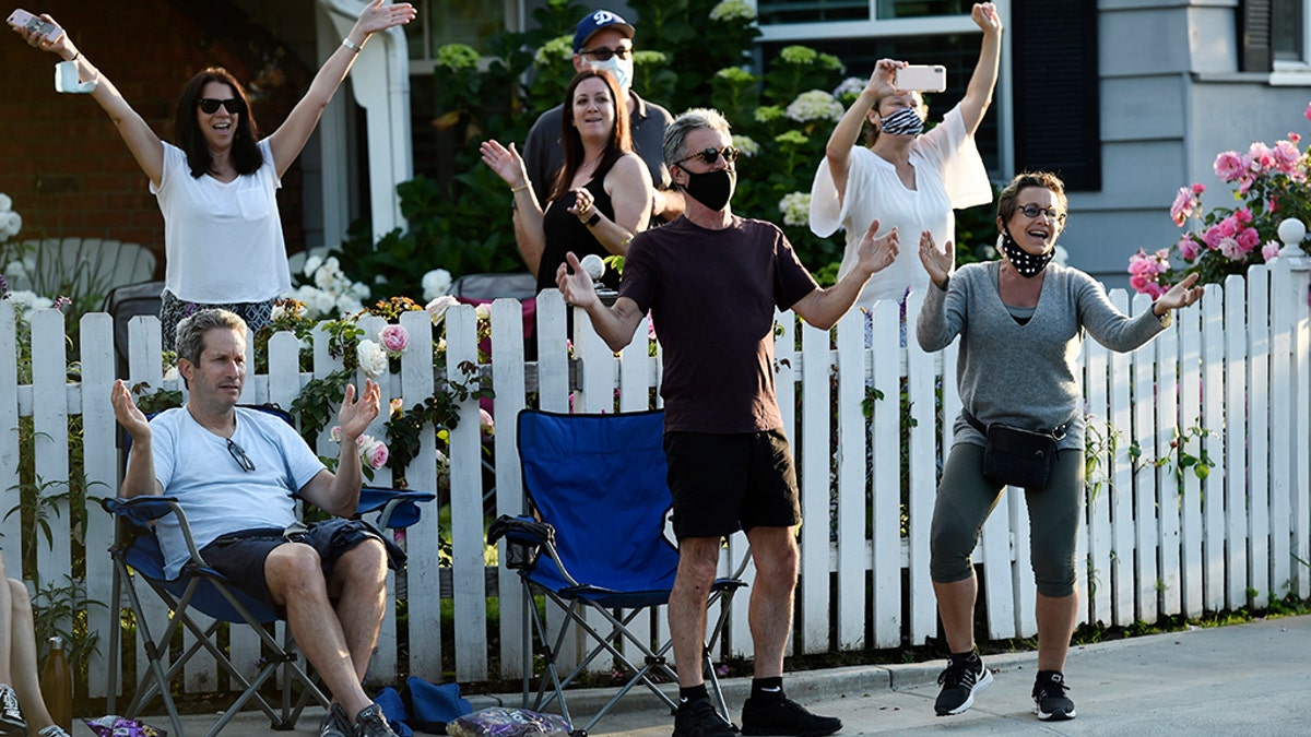 In this May 9, 2020 photo, SAG-AFTRA president Gabrielle Carteris, far right, and her husband Charles Isaacs, center, are among the cheering spectators at musician Adam Chester's weekly neighborhood performance in the Sherman Oaks section of Los Angeles. (AP Photo/Chris Pizzello)