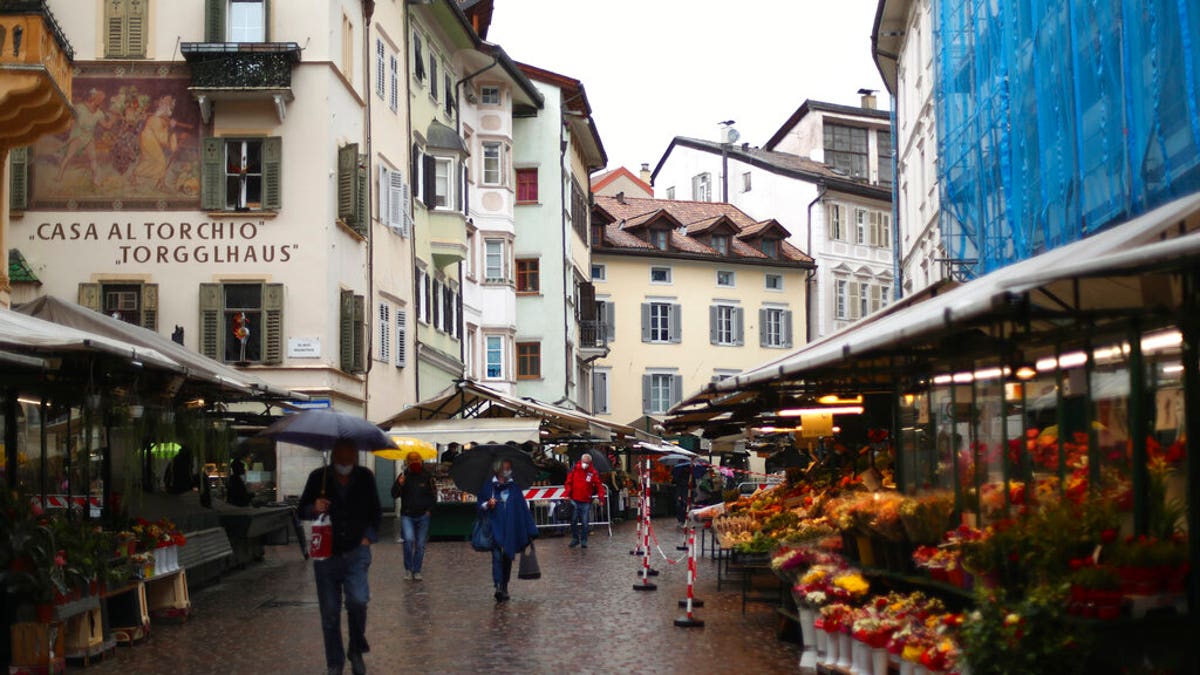 People wearing face masks to protect against the coronavirus walk through the traditional vegetable market in Bolzano, known in German as Bozen, Italy, Monday, May 11, 2020. 