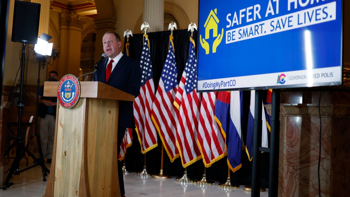 Colorado Gov. Jared Polis makes a point during a news conference to update the state's efforts to check the spread of the new coronavirus on Monday in Denver. Polis announced that a restaurant in Castle Rock, Colo., that opened Sunday in defiance of state rules barring in-person dining will have its business license suspended temporarily for the action. (AP Photo/David Zalubowski)