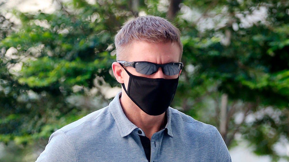 In this May 13, 2020, photo, Brian Dugan Yeargan, wearing a face mask and sunglasses, walks outside the Singapore State Court in Singapore. The 44-year-old American pilot has been jailed for four weeks for breaching a quarantine order in Singapore. Local media reported that Brian Dugan Yeargan was sentenced by a court Wednesday, May 13 for leaving his hotel room for three hours to buy masks and a thermometer. (The Straits Times via AP)