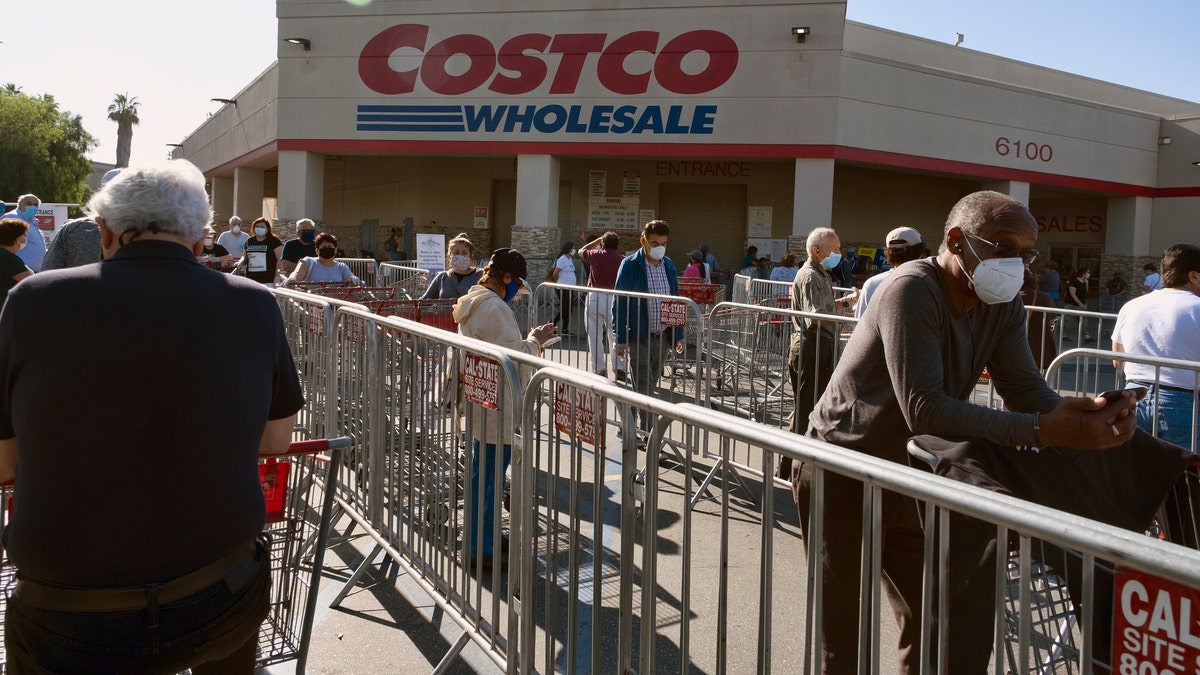 Customers wearing protective masks from the coronavirus and keeping social distancing space line up to enter a Costco Wholesale store in the Van Nuys section of Los Angeles on Saturday. (AP Photo/Richard Vogel)