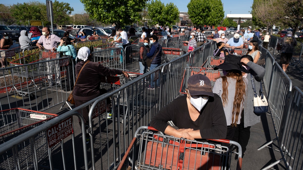 Customers wearing protective masks from the coronavirus and keeping social distancing space line up to enter a Costco Wholesale store in the Van Nuys section of Los Angeles, Saturday, May 16, 2020. (AP Photo/Richard Vogel)