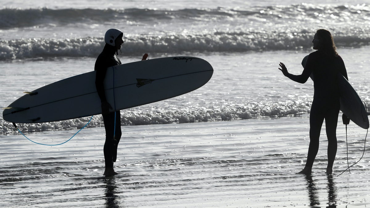 Surfers gesture as the talk before entering the water at Sumner Beach near in Christchurch, New Zealand, May 18. (AP Photo/Mark Baker)