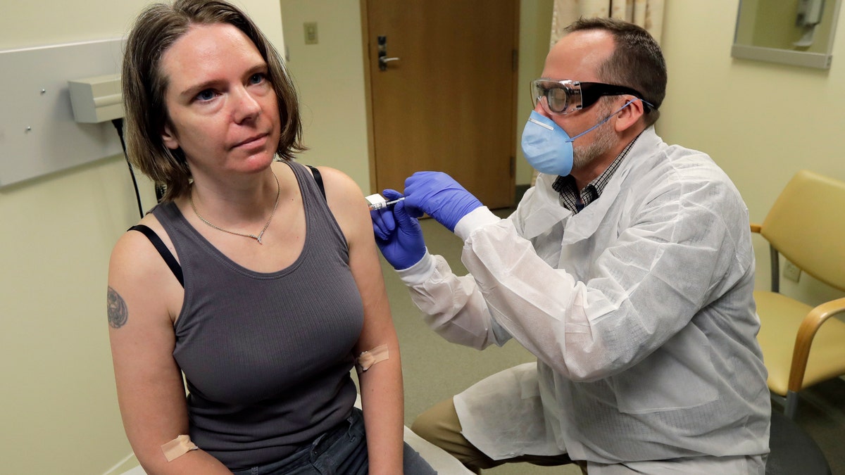 March 16, 2020: A pharmacist gives Jennifer Haller, left, the first shot in the first-stage safety study clinical trial of a potential vaccine for COVID-19, the disease caused by the new coronavirus, at the Kaiser Permanente Washington Health Research Institute in Seattle. The vaccine by Cambridge, Massachusetts-based Moderna Inc., generated antibodies similar to those seen in people who have recovered from COVID-19 in a study volunteers who were given either a low or medium dose.