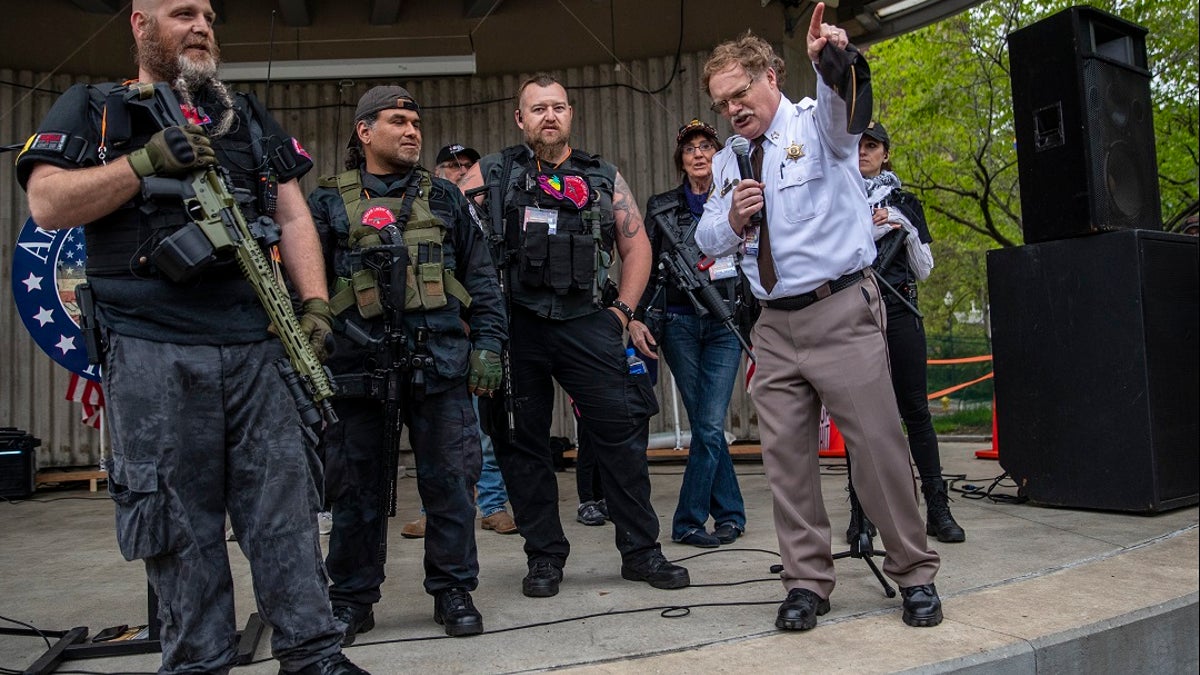 Barry County Sheriff Dar Leaf, front right, speaks next to members of the Michigan Liberty Militia during the "American Patriot Rally-Sheriffs speak out" event at Rosa Parks Circle in downtown Grand Rapids, Mich. The crowd was protesting against Gov. Gretchen Whitmer's stay-at-home order during the coronavirus pandemic. (Cory Morse/The Grand Rapids Press via AP)