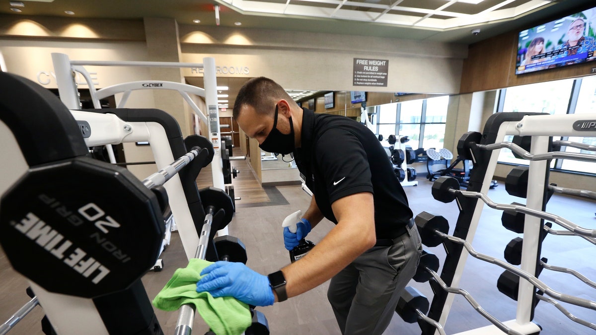 man wipes down gym equipment