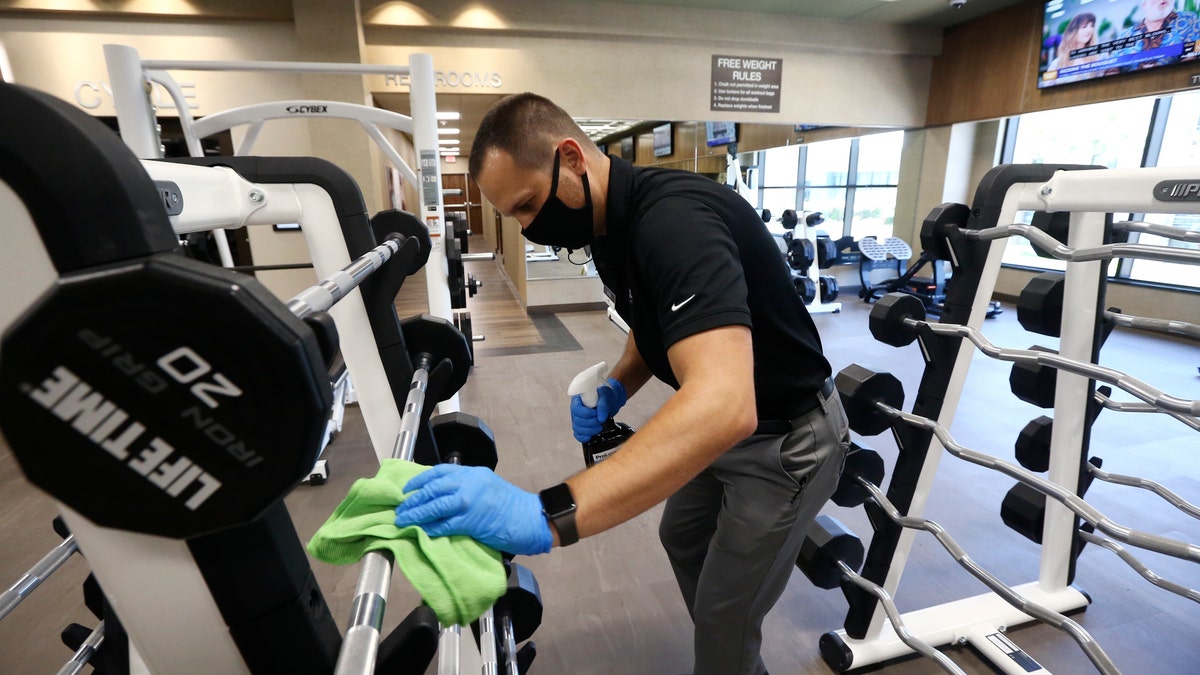 man wipes down gym equipment