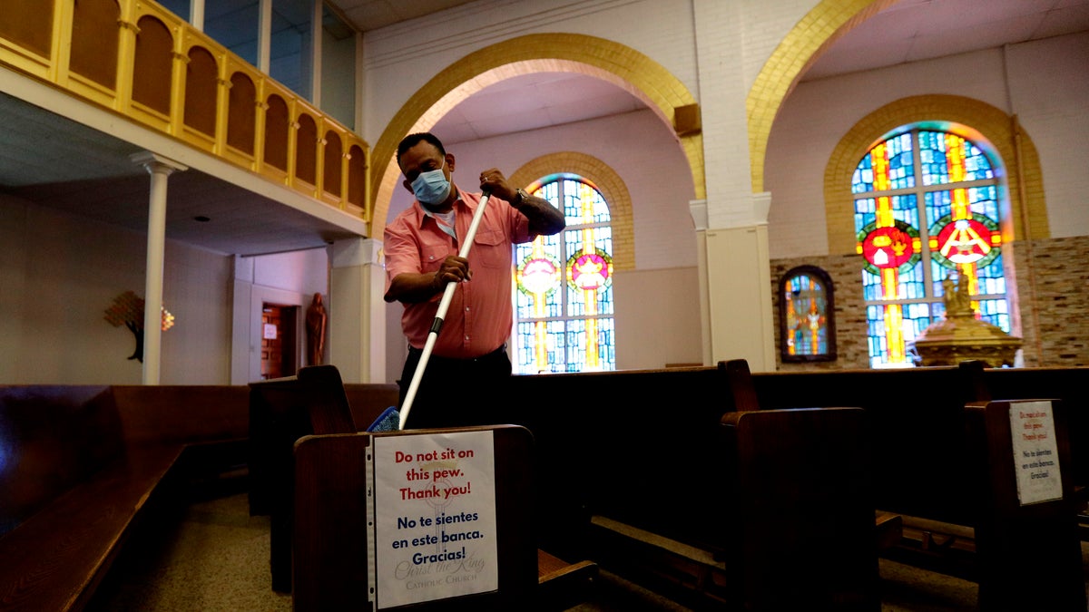 Juan Arriola helps clean and sanitize pews following an in-person Mass at Christ the King Catholic Church in San Antonio, May 19. San Antonio parishes that have been closed due to the COVID-19 pandemic began reopening their doors to in-person services. (AP Photo/Eric Gay)
