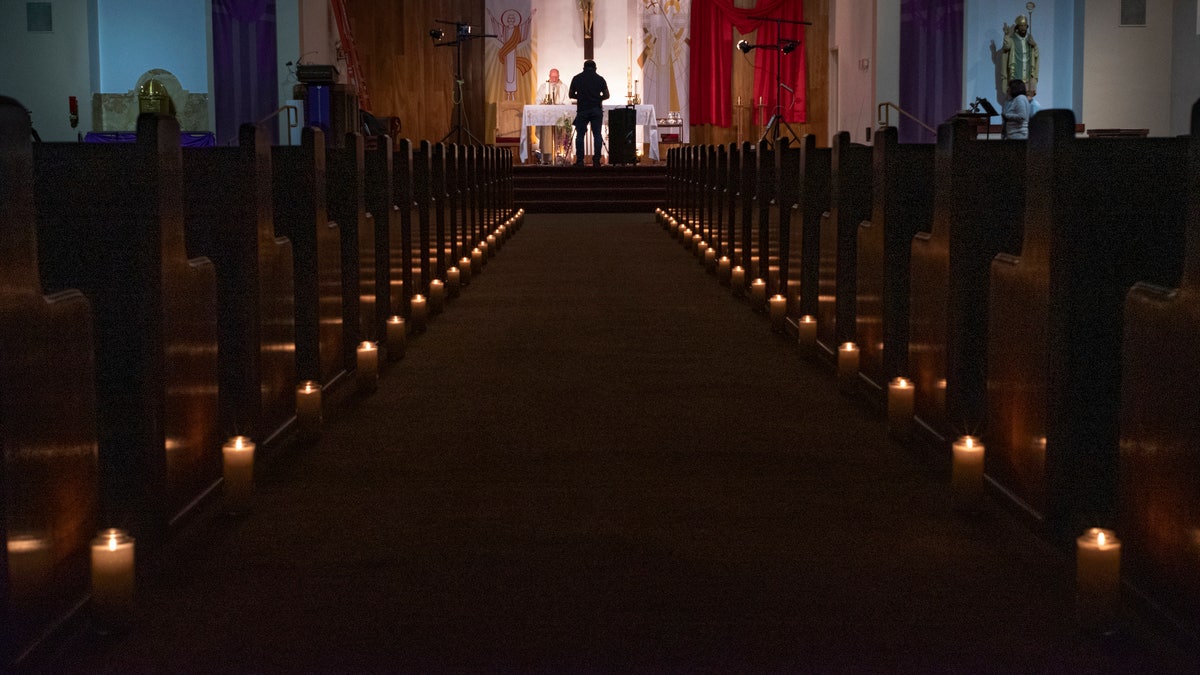 A person films a pastor celebrating Easter Vigil Mass at St. Patrick Church in North Hollywood, Calif on April 11, 2020. The head of the federal Justice Department's Civil Rights Division told Gov. Gavin Newsom Tuesday, May 19, 2020, that his plan to reopen California discriminates against churches. (AP Photo/Damian Dovarganes)