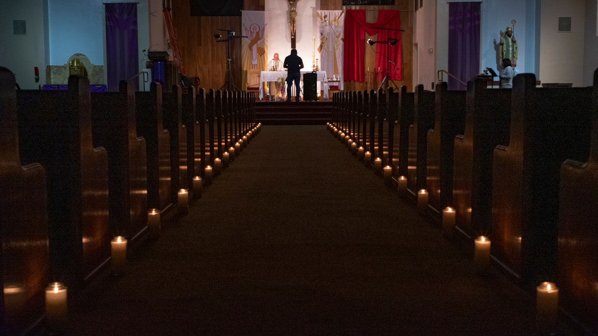 A person films a pastor celebrating Easter Vigil Mass at St. Patrick Church in North Hollywood, Calif on April 11, 2020. The head of the federal Justice Department's Civil Rights Division told Gov. Gavin Newsom Tuesday, May 19, 2020, that his plan to reopen California discriminates against churches. (AP Photo/Damian Dovarganes)