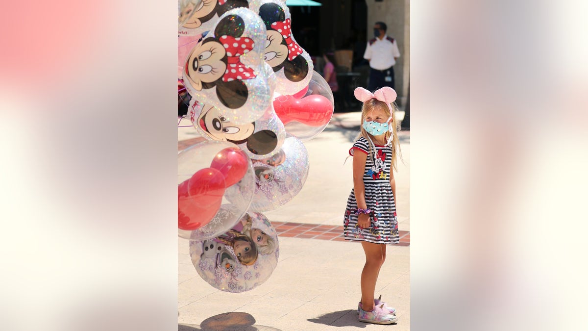 A girl gazes at Mickey Mouse balloons at Disney Springs in Orlando on May 20. Walt Disney World's shopping and dining complex is beginning the first phase of getting back to business. (Stephen M. Dowell/Orlando Sentinel via AP)