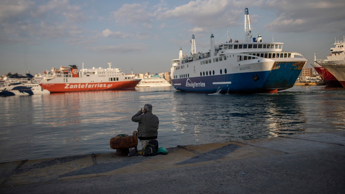 A man sits on the dock at the port of Piraeus, near Athens, on Monday, May 25, 2020. Greece restarted Monday regular ferry services to the islands as the country accelerated efforts to salvage its tourism season. (AP Photo/Petros Giannakouris)