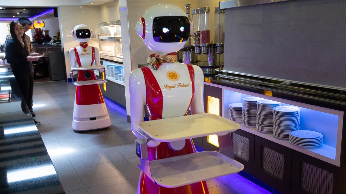 The owners of the Royal Palace restuarant in Renesse, southwestern Netherlands, demonstrate the use of robots for serving purposes, or for the collection of dirty dishes, as part of a tryout process aimed at helping to curb the spread of the coronavirus. (AP Photo/Peter Dejong)
