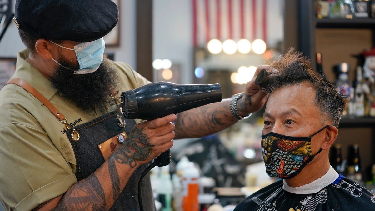 Luis Lopez wears a face mask while giving a hair cut to Alexander Chin at Orange County Barbers Parlor on May 27. (AP Photo/Ashley Landis)