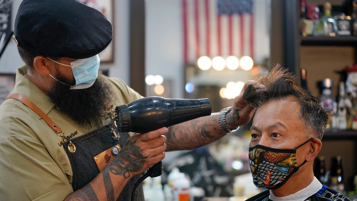 Luis Lopez wears a face mask while giving a hair cut to Alexander Chin at Orange County Barbers Parlor on May 27. (AP Photo/Ashley Landis)