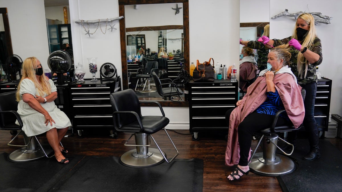 Sandy Crabb, left, chats with Jan Borden as Susie Smith applies color to Borden's hair at Makin Waves salon on May 27 in Huntington Beach, Calif. (AP Photo/Ashley Landis)