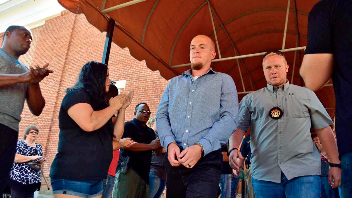 A file image of former police officer Canyon Boykin, center, being led from the Lowndes County Courthouse in handcuffs while people applauded in Columbus, Miss. 