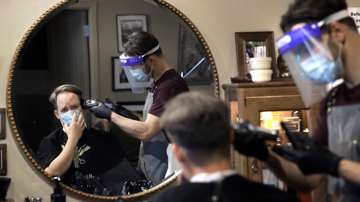 Vin Norton, of Wellesley, Mass., left, gets his hair cut by barber Cristian Lopez, of Sherborn, Mass., at Barber Walter's barbershop, as they both wear masks out of concern for the coronavirus on May 26. (AP Photo/Steven Senne)