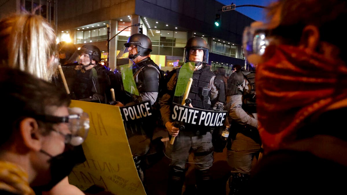 Protesters stand in front of Kentucky State Police officers as they protest the deaths of George Floyd and Breonna Taylor, Friday, May 29, 2020, in Louisville, Ky. Breonna Taylor, a black woman, was fatally shot by police in her home in March.?