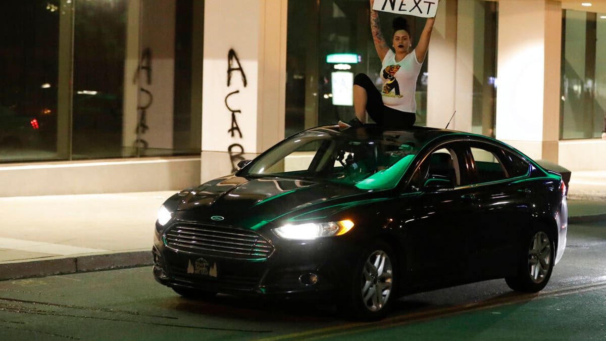 A protester rides on the top of a car during a protest over the deaths of George Floyd and Breonna Taylor, Friday, May 29, 2020, in Louisville, Ky. Breonna Taylor, a black woman, was fatally shot by police in her home in March.