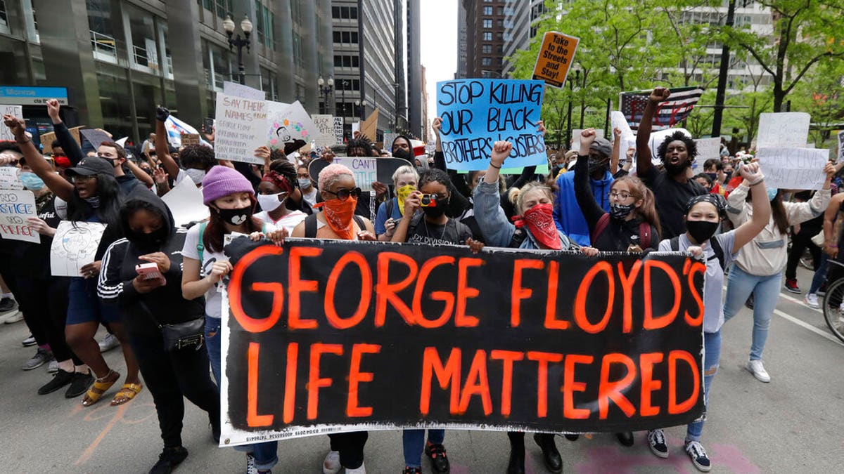 Protesters hold signs as they march during a protest over the death of George Floyd in Chicago, Saturday, May 30, 2020. 
