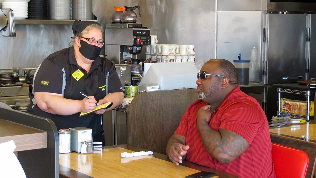 Corey Brooks, right, orders food at a Waffle House restaurant in Savannah, Georgia, on Monday, April 27, 2020. Restaurants statewide were allowed to resume dine-in service with restrictions after a month of being limited to takeout orders because of the coronavirus.