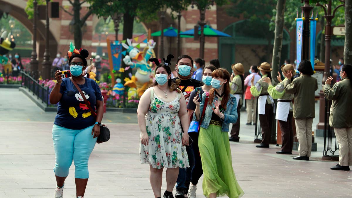 Visitors wearing face masks are seen at Shanghai Disney Resort on May 11 in Shanghai, China.