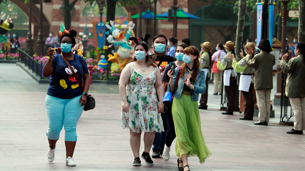 Visitors wearing face masks are seen at Shanghai Disney Resort on May 11 in Shanghai, China.