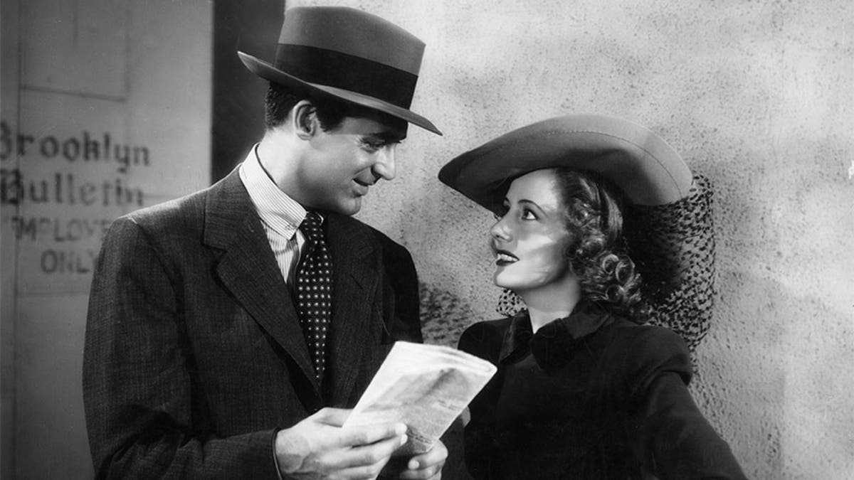 British-born actor Cary Grant (1904-1986) holds a folded newspaper and looks at American actor Irene Dunne (1898-1990) while they stand outside the employee's entrance of the Brooklyn Bulletin, in a still from director George Stevens's film, 'Penny Serenade.'