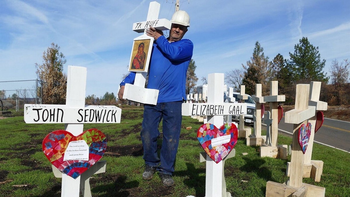 Carpenter Greg Zanis sets up wooden crosses in memory of the dead of the "Camp" fire in the Paradise area at the entrance to the village along the main access road. Zanis made wooden crosses in memory of deaths from mass shootings and other incidents. Photo: Barbara Munker/dpa (Photo by Barbara Munker/picture alliance via Getty Images)