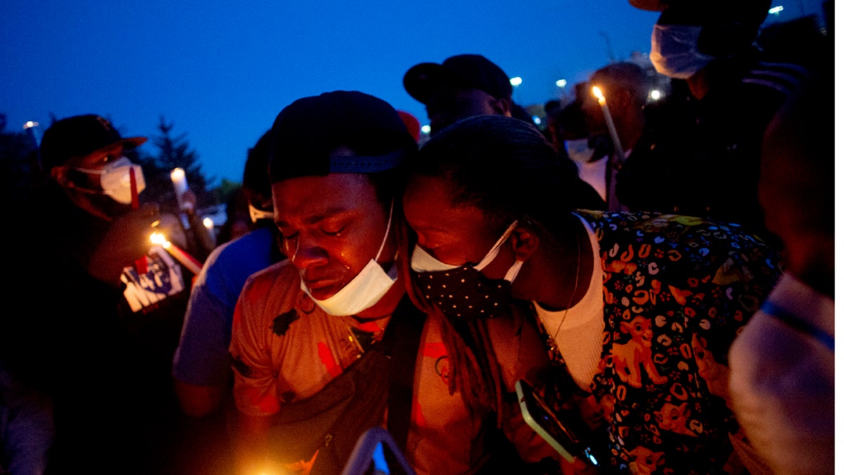 Maalik Mitchell, center left, shedding tears as he said goodbye to his father, Calvin Munerlyn, during a vigil Sunday in Flint, Mich. (Jake May/The Flint Journal via AP)