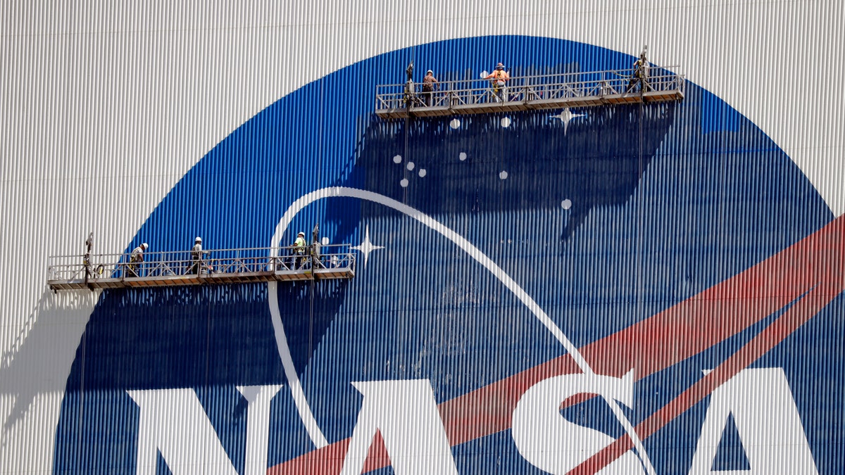 Workers near the top of the 526 ft. Vehicle Assembly Building at the Kennedy Space Center spruce up the NASA logo standing on scaffolds in Cape Canaveral, Fla., Wednesday, May 20, 2020. (Associated Press)