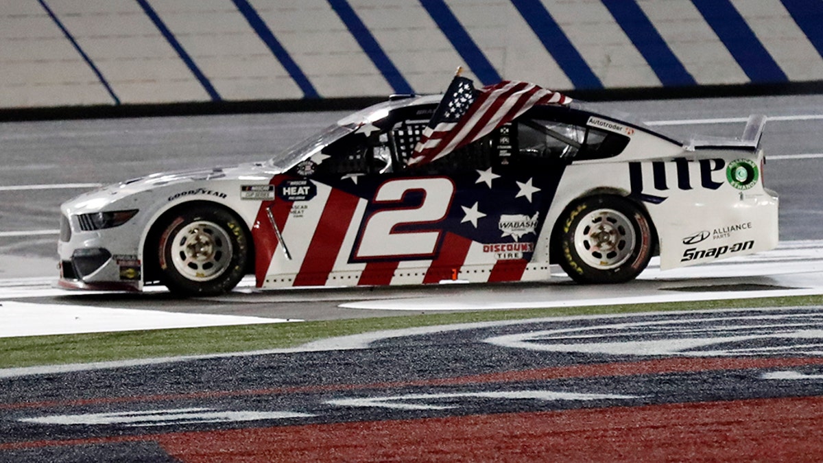 Brad Keselowski holds an American flag after winning the NASCAR Cup Series auto race at Charlotte Motor Speedway early Monday, May 25, 2020, in Concord, N.C. (AP Photo/Gerry Broome)