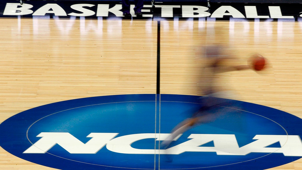 FILE - In this March 14, 2012, file photo, a player runs across the NCAA logo during practice in Pittsburgh before an NCAA tournament college basketball game.