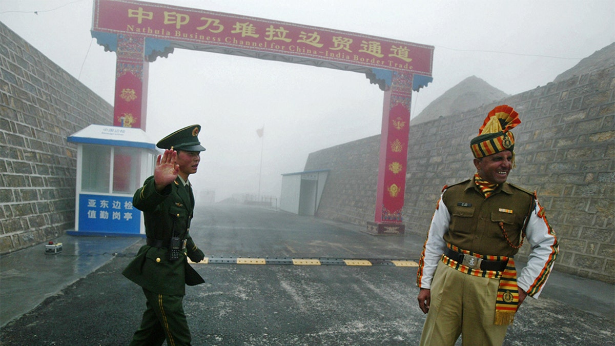 A Chinese soldier (L) and an Indian soldier stand guard at the Chinese side of the ancient Nathu La border crossing between India and China. (DIPTENDU DUTTA/AFP via Getty Images)