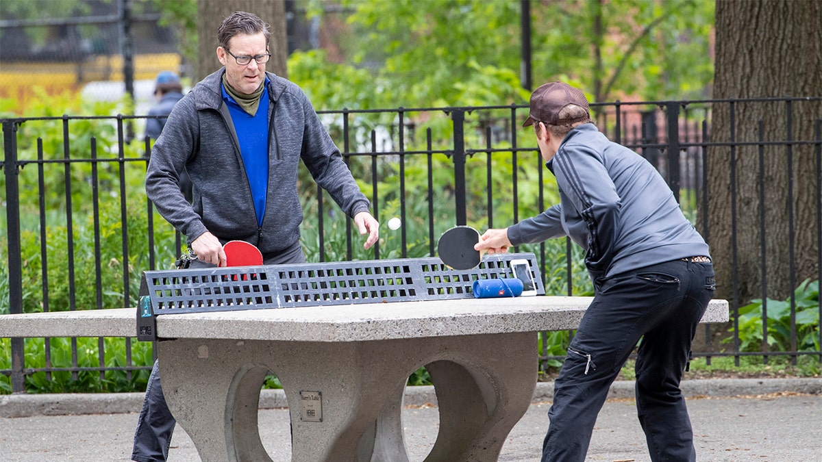 In this Monday, May 11, 2020 photo, men play ping pong without face masks at Tompkins Square Park in New York. New York's governor has ordered masks for anyone out in public who can't stay at least six feet away from other people. Yet, while the rule is clear, New Yorkers have adopted their own interpretation of exactly when masks are required, especially outdoors. (AP Photo/Mary Altaffer)