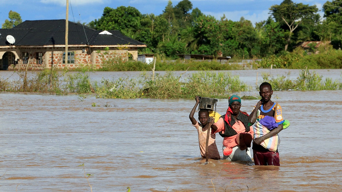 Residents wade through the waters after their home was flooded after the River Nzoia burst its banks and due to heavy rainfall and the backflow from Lake Victoria, in Budalangi within Busia County, Kenya May 3, 2020.