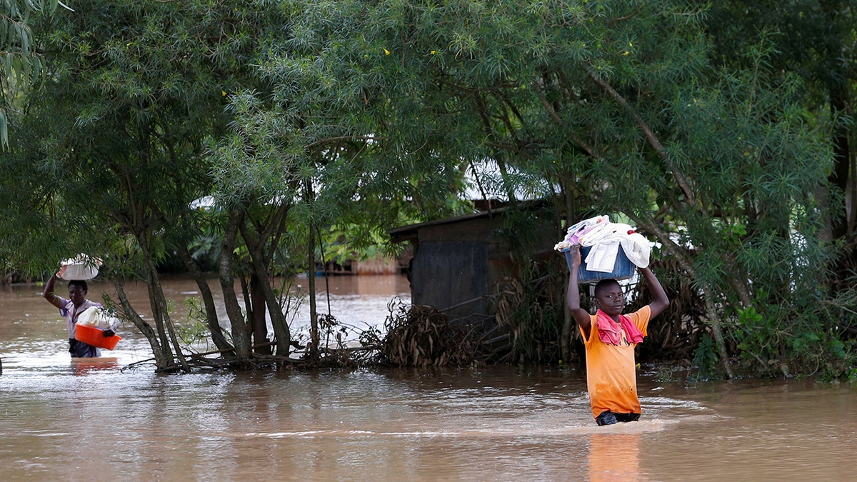 Residents carry their belongings inside flood water as they evacuate from their home after River Nzoia burst its banks and due to the backflow from Lake Victoria, in Nyadorera, Siaya County, Kenya May 2, 2020.