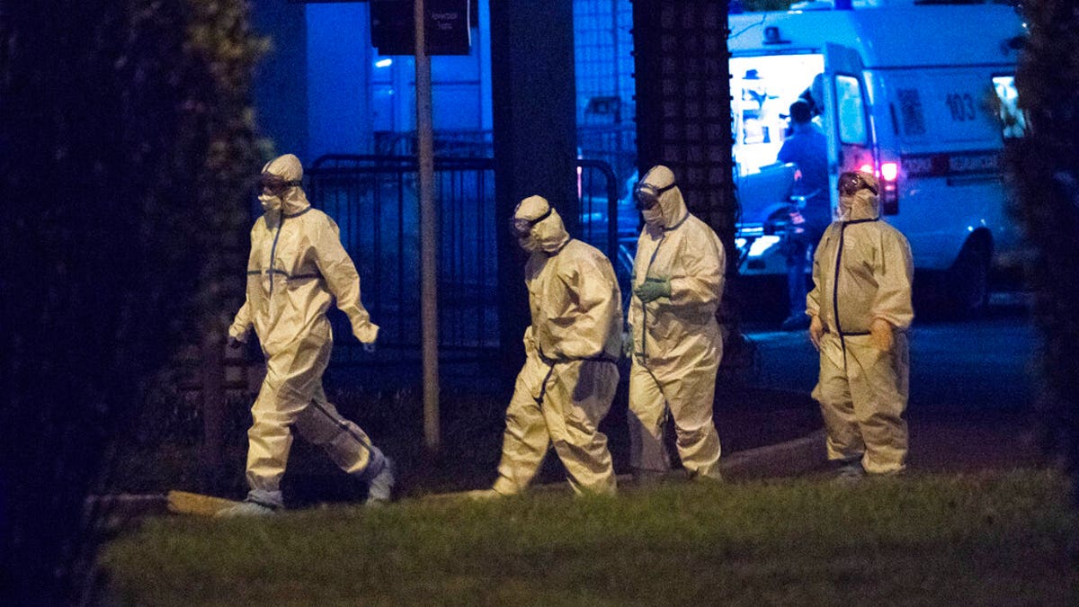 Medical workers wearing protective gear walk after an evacuation at Spasokukotskogo Hospital in Moscow, Russia, on Saturday. A fire at a Moscow hospital treating people infected by the coronavirus killed one patient and forced the evacuation of about 200 others. (AP)