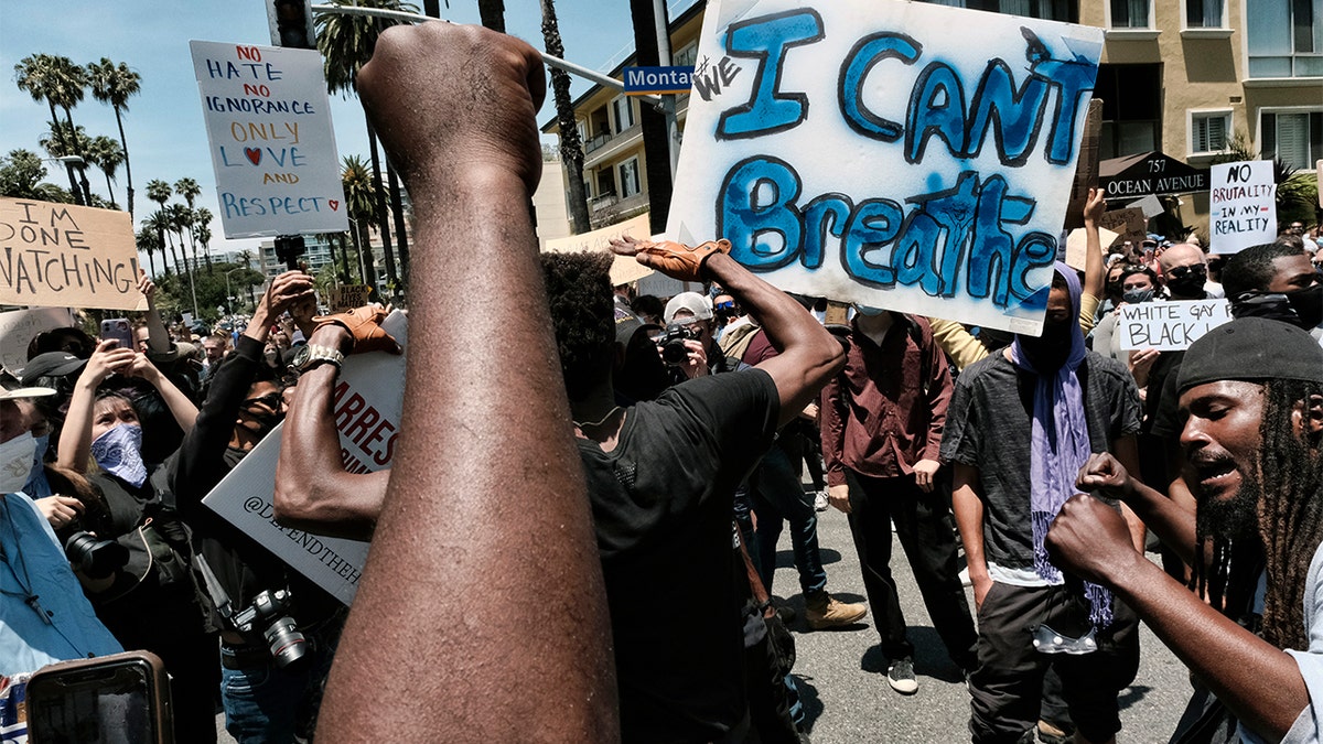 Protesters chant and raise their fists while blocking traffic on a street corner in Santa Monica, Calif., Sunday, May 31, 2020, over the death of George Floyd, a black man who died May 25 after he was pinned at the neck by a Minneapolis police officer. (AP Photo/Richard Vogel)