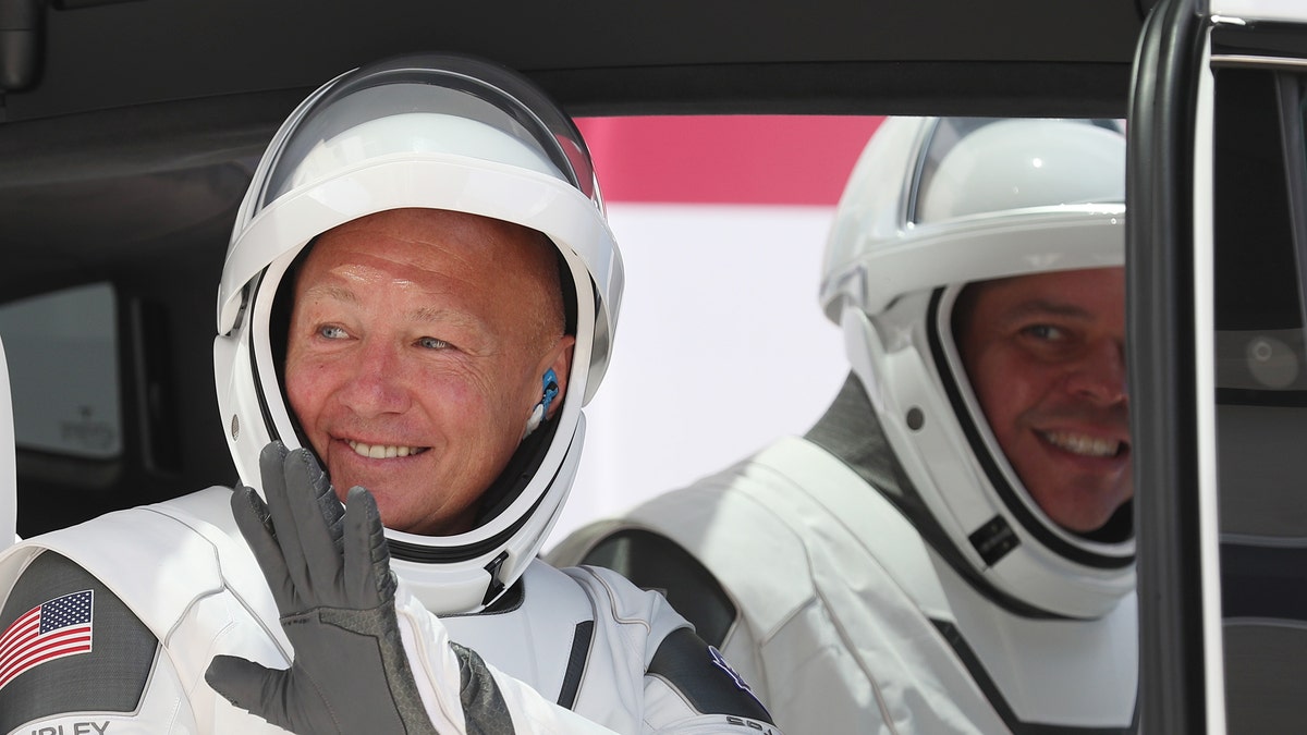NASA astronauts Bob Behnken (R) and Doug Hurley sit in a Tesla vehicle after walking out of the Operations and Checkout Building on their way to the SpaceX Falcon 9 rocket with the Crew Dragon spacecraft on launch pad 39A at the Kennedy Space Center on May 30, 2020 in Cape Canaveral, Florida.